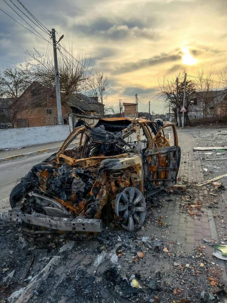 A burnt car in Borodyanka, Ukraine, illustrates urban destruction and abandonment.